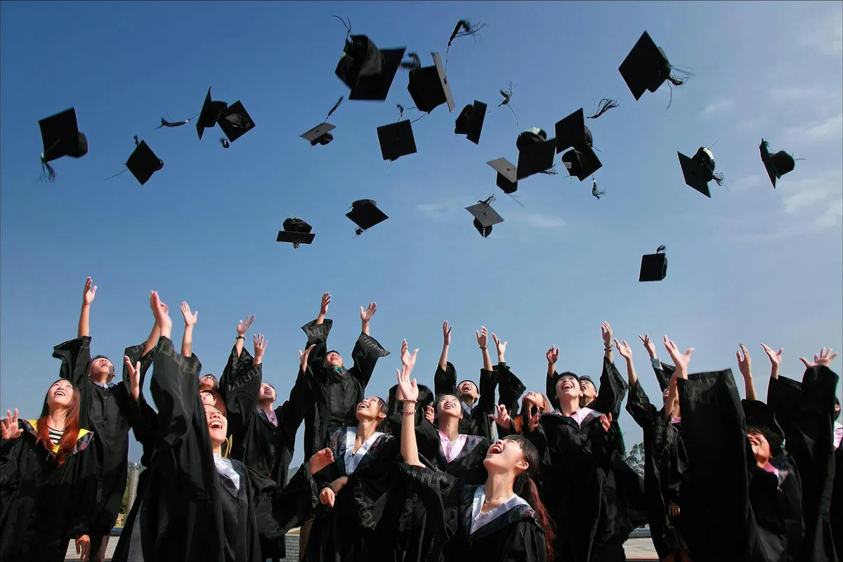 International students celebrating graduation by throwing their caps in the air